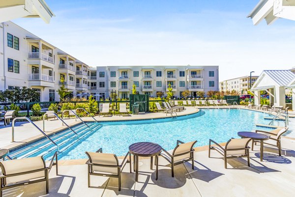 Resort-style pool with sun loungers and lush landscaping at Town Center at Berry Farms Apartments