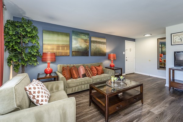 Spacious living room with modern decor and large windows at Ravens Crest Apartments