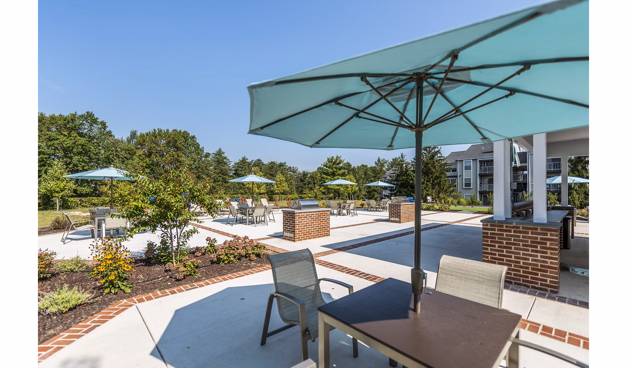 Outdoor grill area at Ravens Crest Apartments with BBQ stations and seating, ideal for social gatherings in a luxury community setting