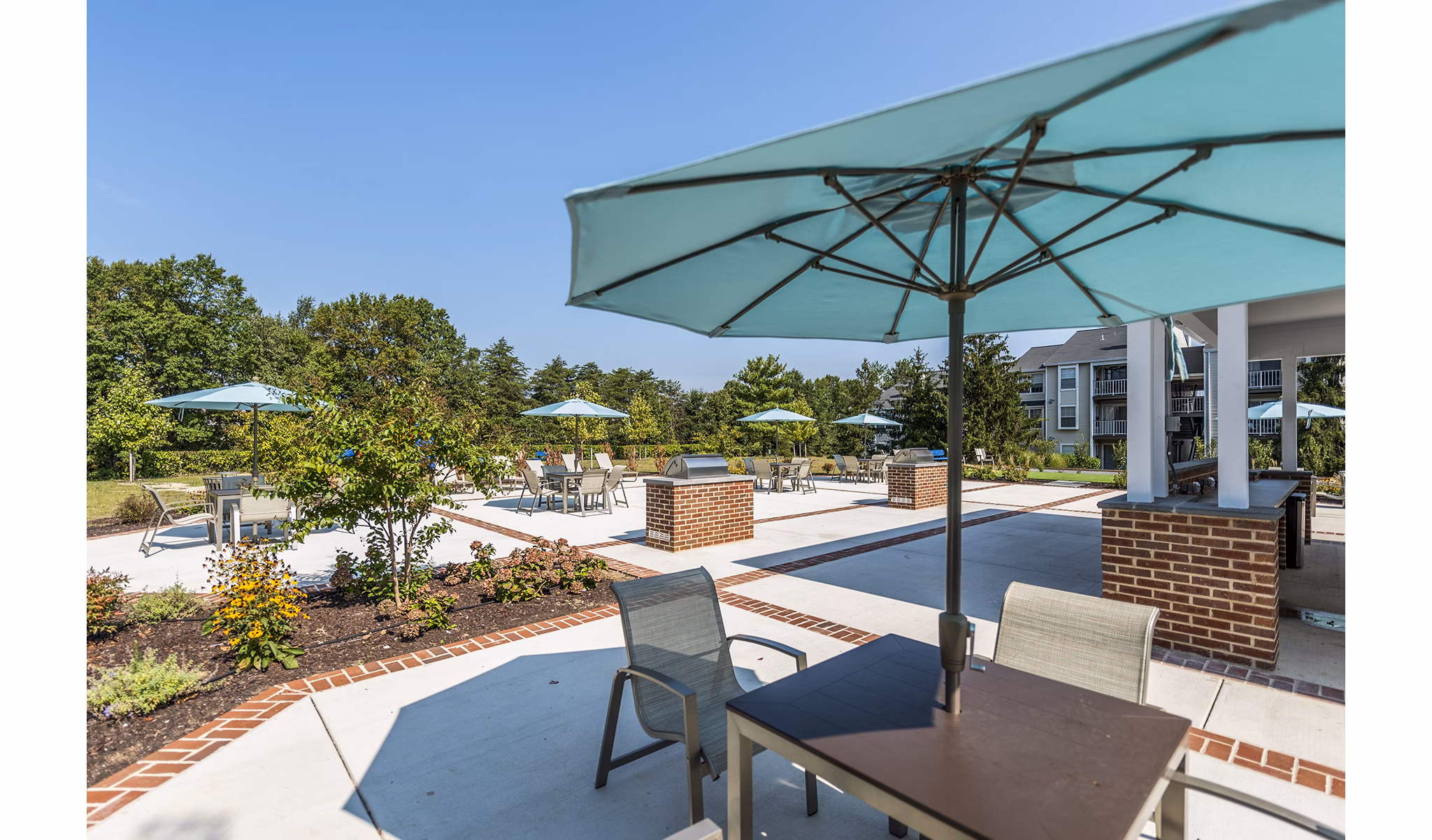 Outdoor grill area at Ravens Crest Apartments with BBQ stations and seating, ideal for social gatherings in a luxury community setting