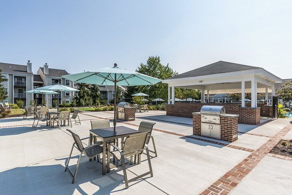 Outdoor grill area with modern seating at Ravens Crest Apartments, ideal for social gatherings and dining al fresco