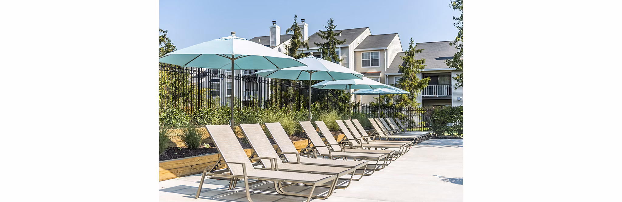 Relaxing poolside lounge chairs at Ravens Crest Apartments