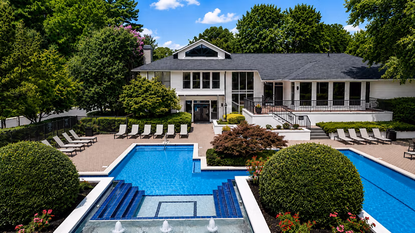 Serene outdoor pool at Avana Chase Apartments with lush landscaping, perfect for relaxation in a luxury setting
