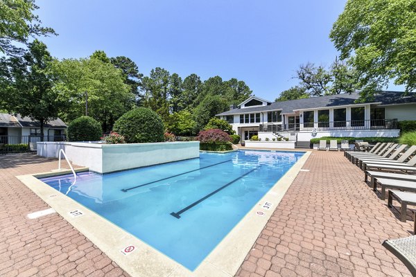 Serene outdoor pool at Avana Chase Apartments with lush landscaping, perfect for relaxation in a luxury setting