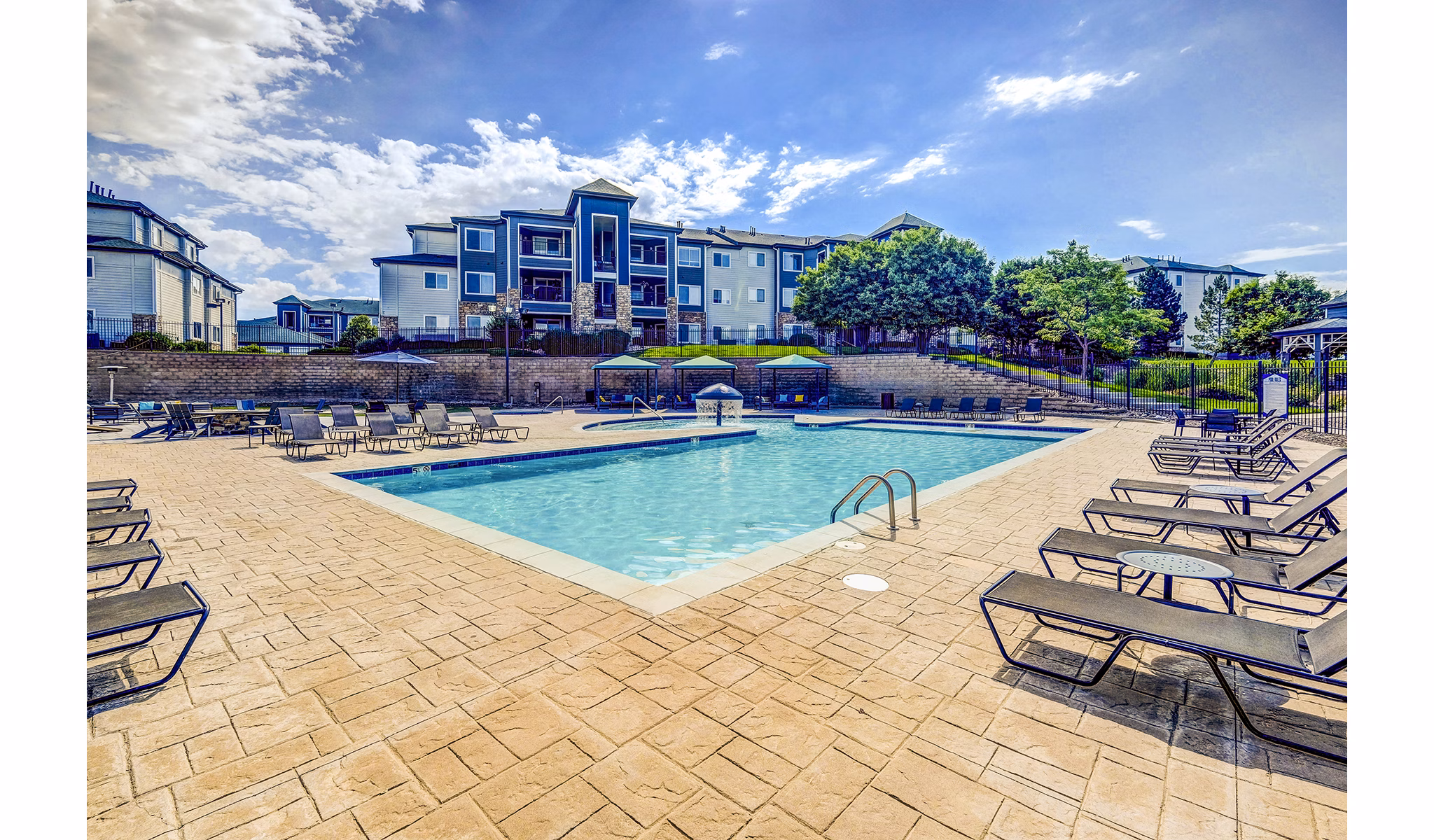 Pool with comfortable seating at The Fletcher Southlands Apartments, offering luxurious relaxation and leisure in a stunning outdoor setting