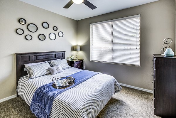 Cozy bedroom with large windows at Laguna at Arrowhead Ranch Apartments
