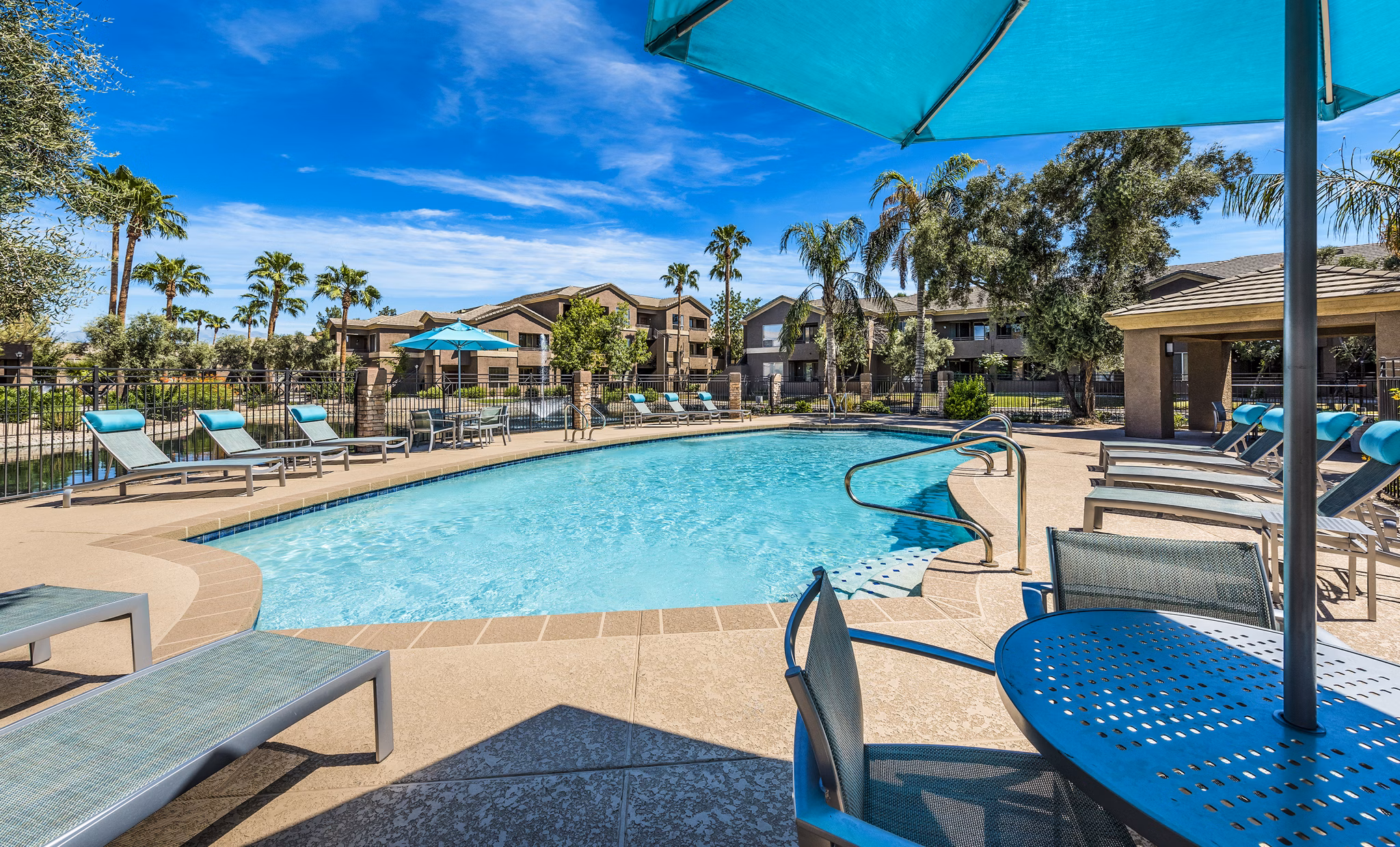 Outdoor pool with palm trees at Laguna at Arrowhead Ranch Apartments, offering a luxurious relaxation spot in Glendale