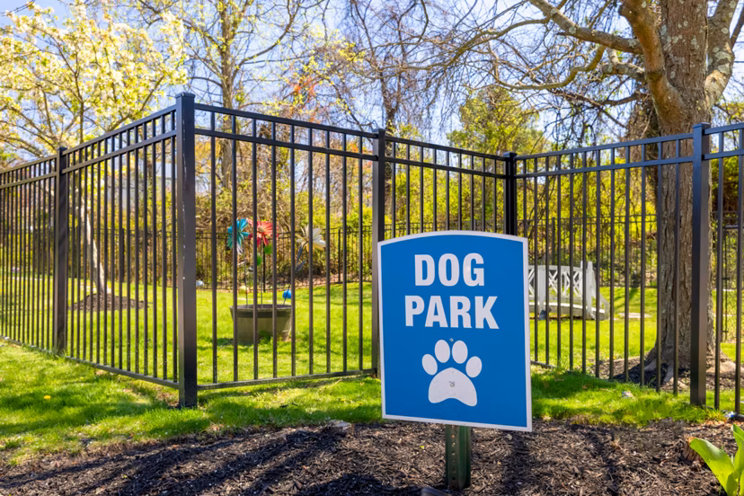 Spacious dog park at HeatherGate at Oxford Valley Apartments with lush greenery and shaded seating areas for residents and their pets