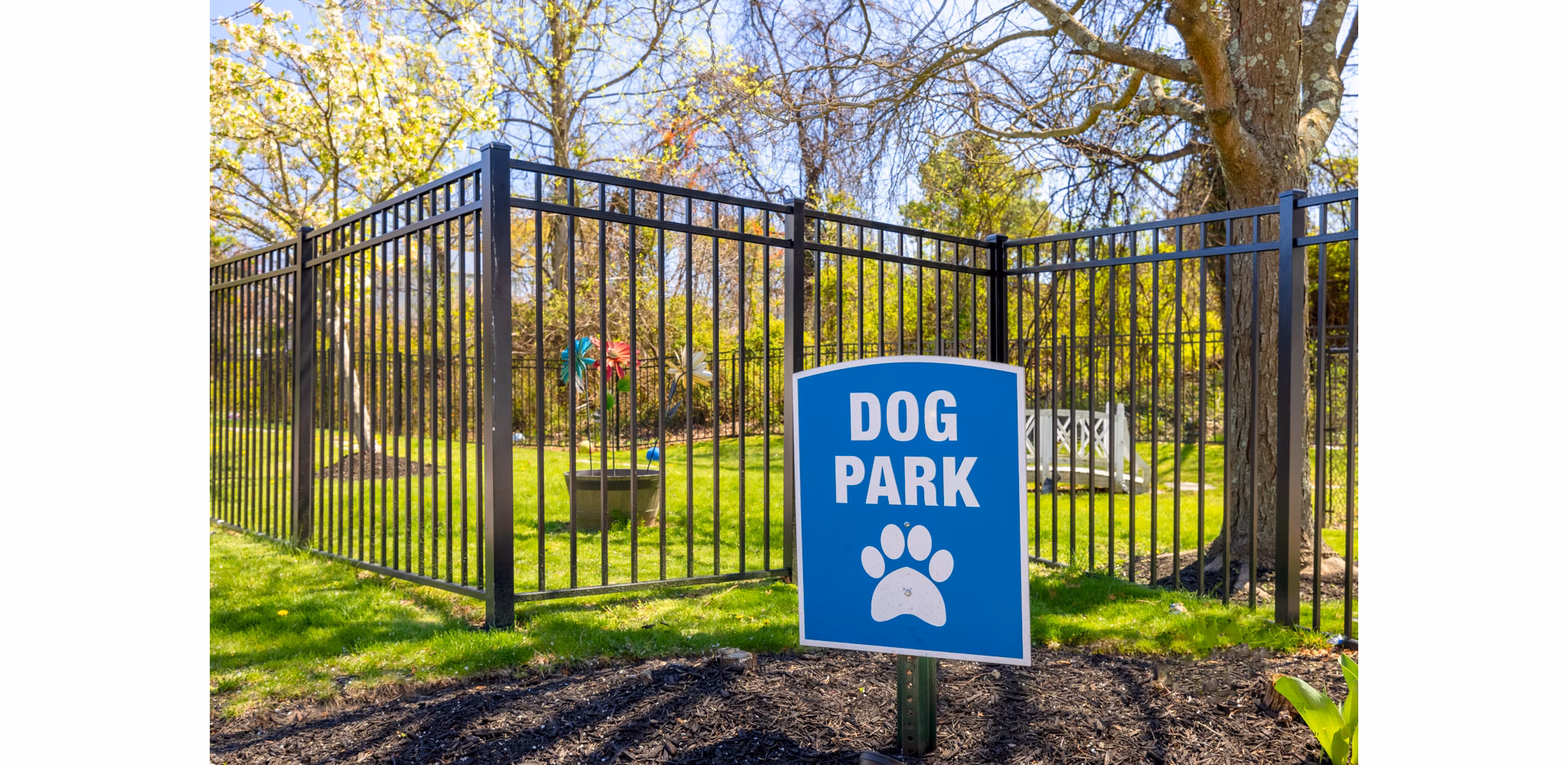 Spacious dog park at HeatherGate at Oxford Valley Apartments with lush greenery and shaded seating areas for residents and their pets