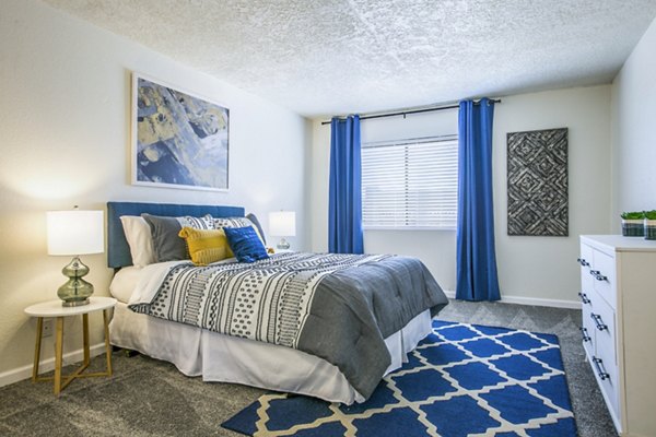 Cozy bedroom with modern decor at Stride West Apartments, featuring large windows and ample natural light