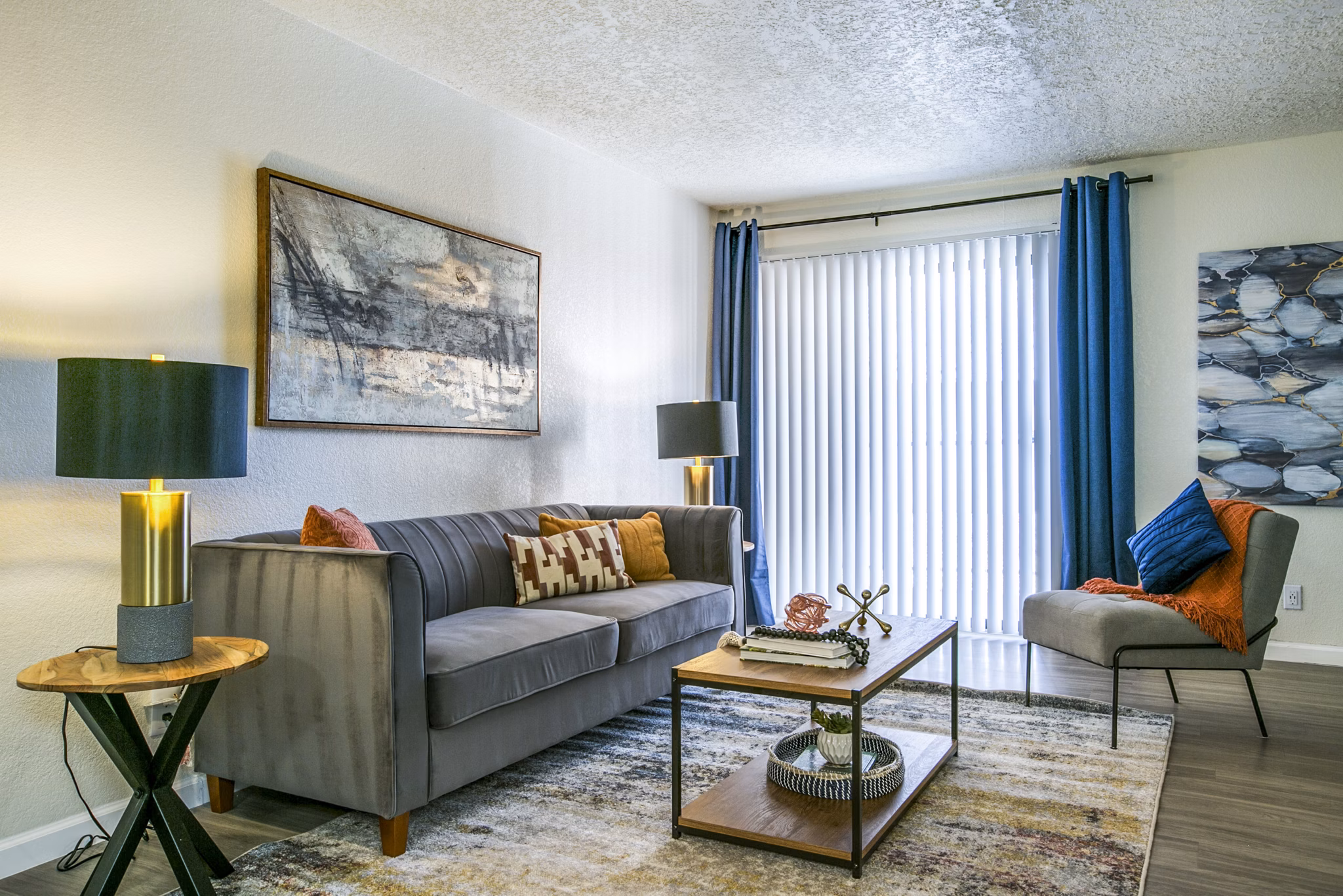 Modern living room with cozy seating and large windows at Stride West Apartments