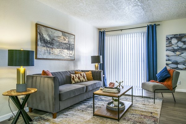 Modern living room with cozy seating and large windows at Stride West Apartments