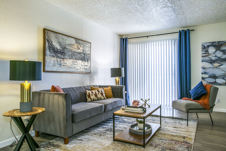 Modern living room with cozy seating and large windows at Stride West Apartments