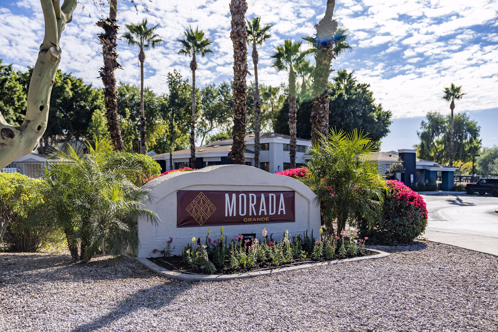 Morada Grande sign surrounded by lush landscaping, featuring palm trees and colorful flowering plants