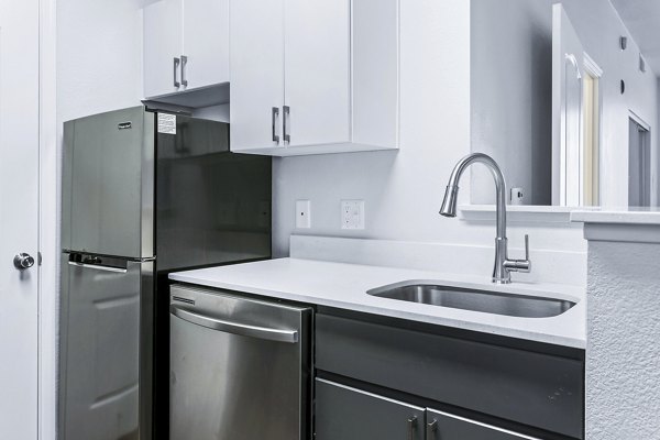 Modern kitchen with sleek appliances and island at The Urban Apartments