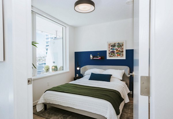 Cozy bedroom with modern furnishings at REN Apartments, showcasing luxury and comfort in an upscale city living environment