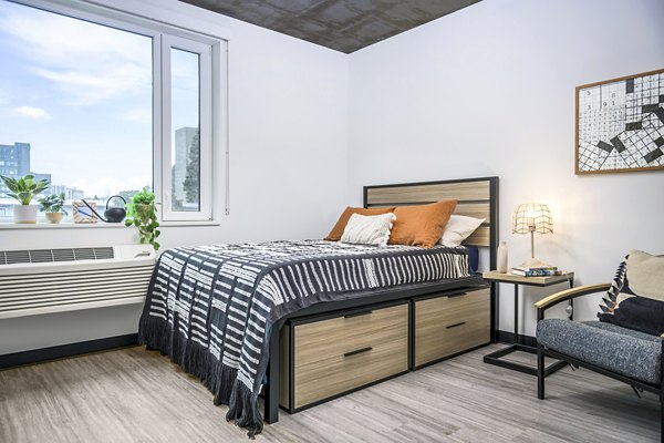 Bedroom with modern furnishings and city views at Union on Broadway Apartments