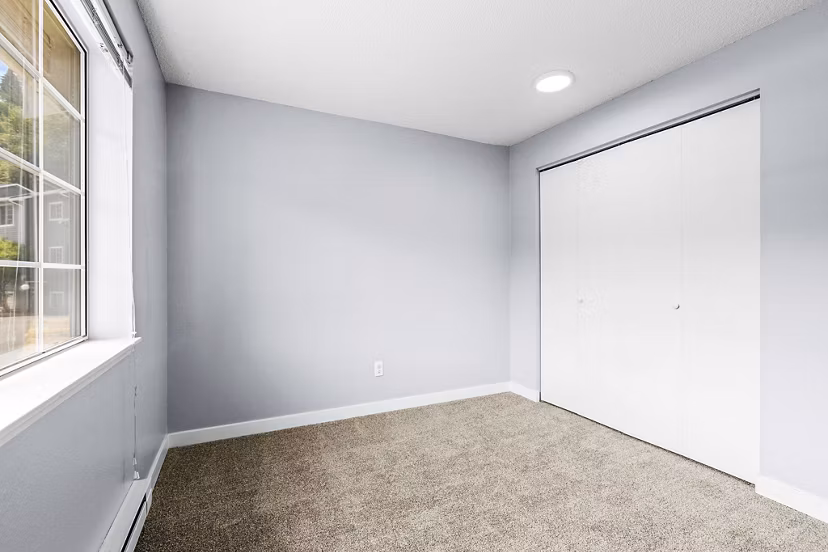 Bedroom with modern decor and large windows at Avana West Hill Apartments