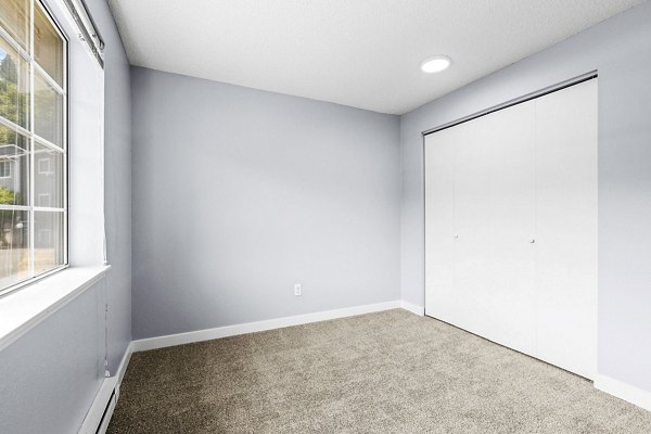 Bedroom with modern decor and large windows at Avana West Hill Apartments