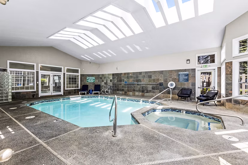 Refreshing outdoor pool at Avana West Hill Apartments with modern lounge chairs and scenic views