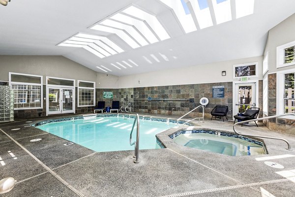 Refreshing outdoor pool at Avana West Hill Apartments with modern lounge chairs and scenic views