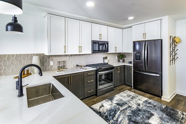 Modern kitchen with sleek cabinetry and stainless steel appliances in Harlowe Apartments