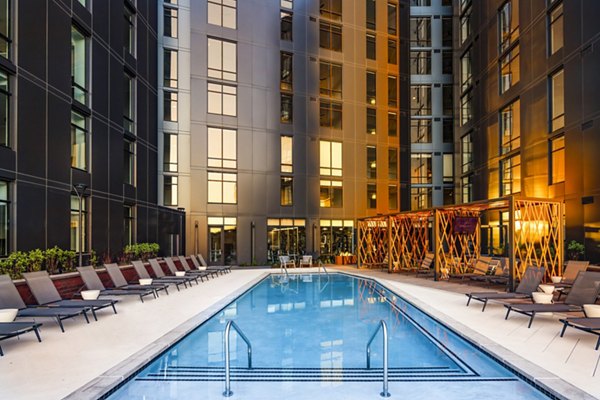 Luxurious pool at Harlowe Apartments with sun loungers and modern landscaping, perfect for relaxation and leisure activities