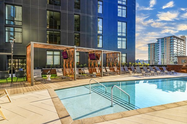 Relaxing pool patio with loungers and greenery at Harlowe Apartments, offering luxurious living in a vibrant community