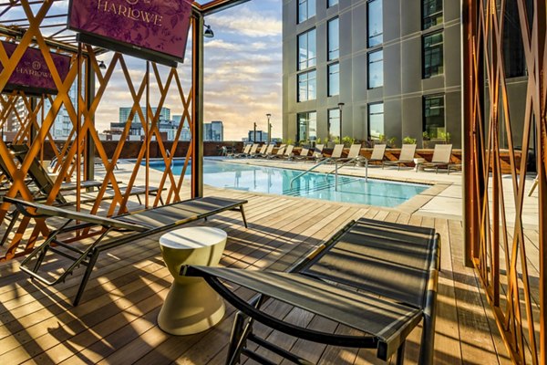 Harlowe Apartments: Luxurious pool patio with stylish loungers and greenery, perfect for relaxing and socializing outdoors