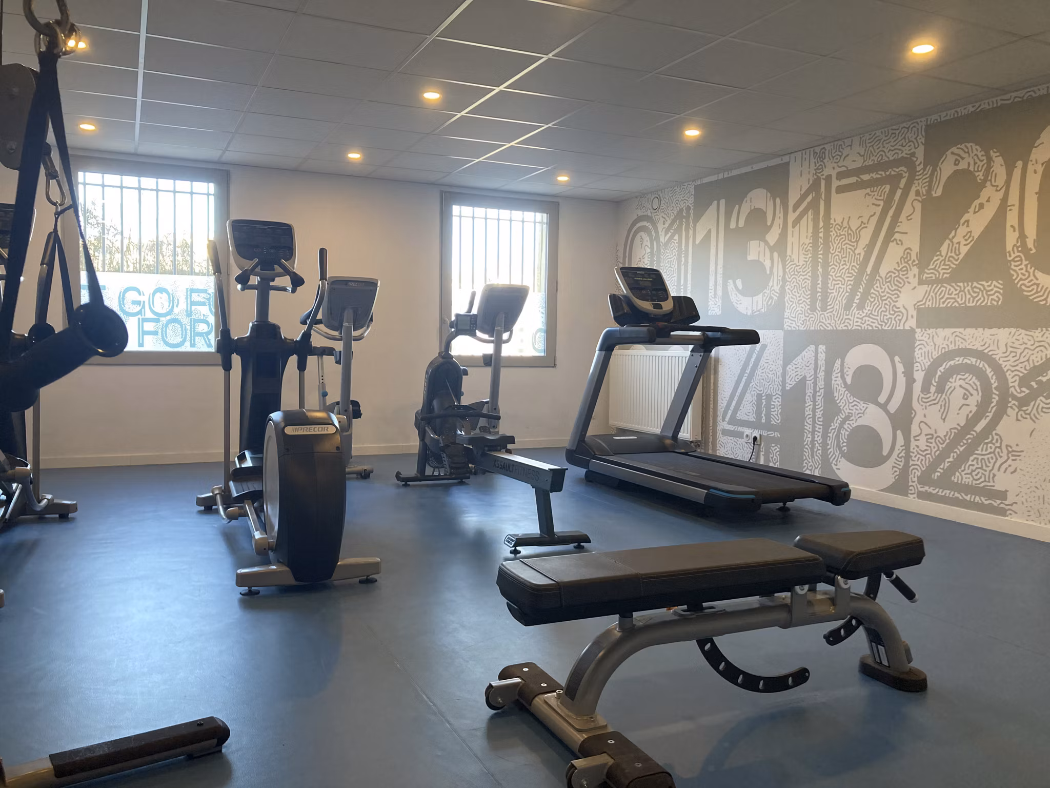 Fitness room featuring treadmills, a variety of weights, and gym equipment set against a large window for natural light.