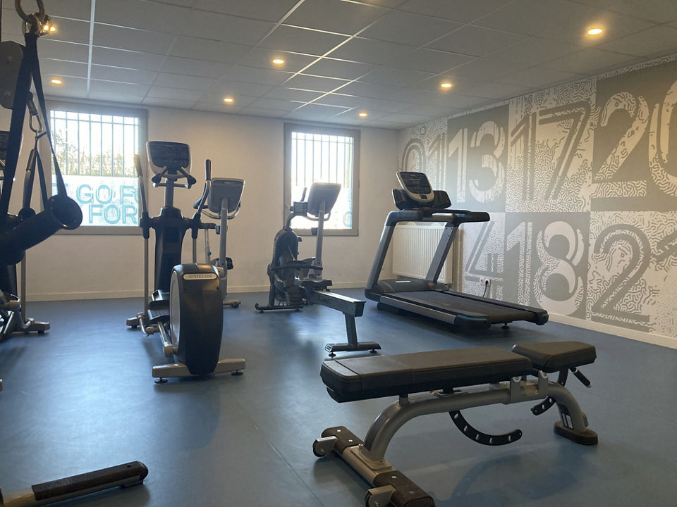 Fitness room featuring treadmills, a variety of weights, and gym equipment set against a large window for natural light.