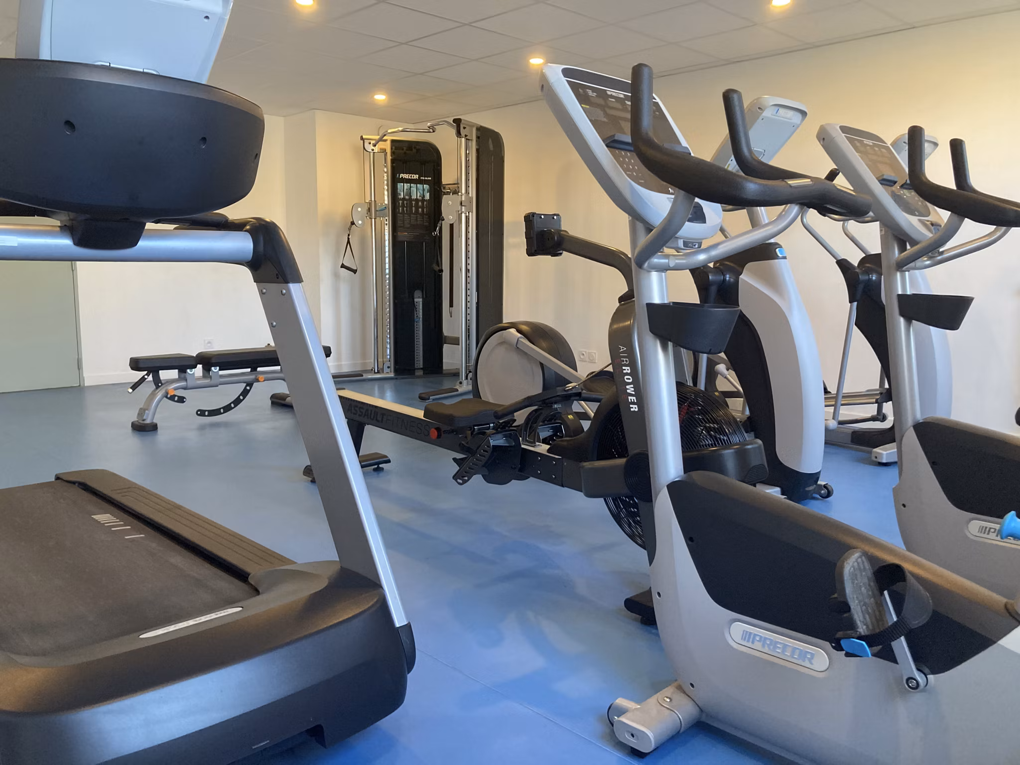 Well-equipped gym space with exercise machines, large mirrors, and bright lighting designed for fitness enthusiasts.