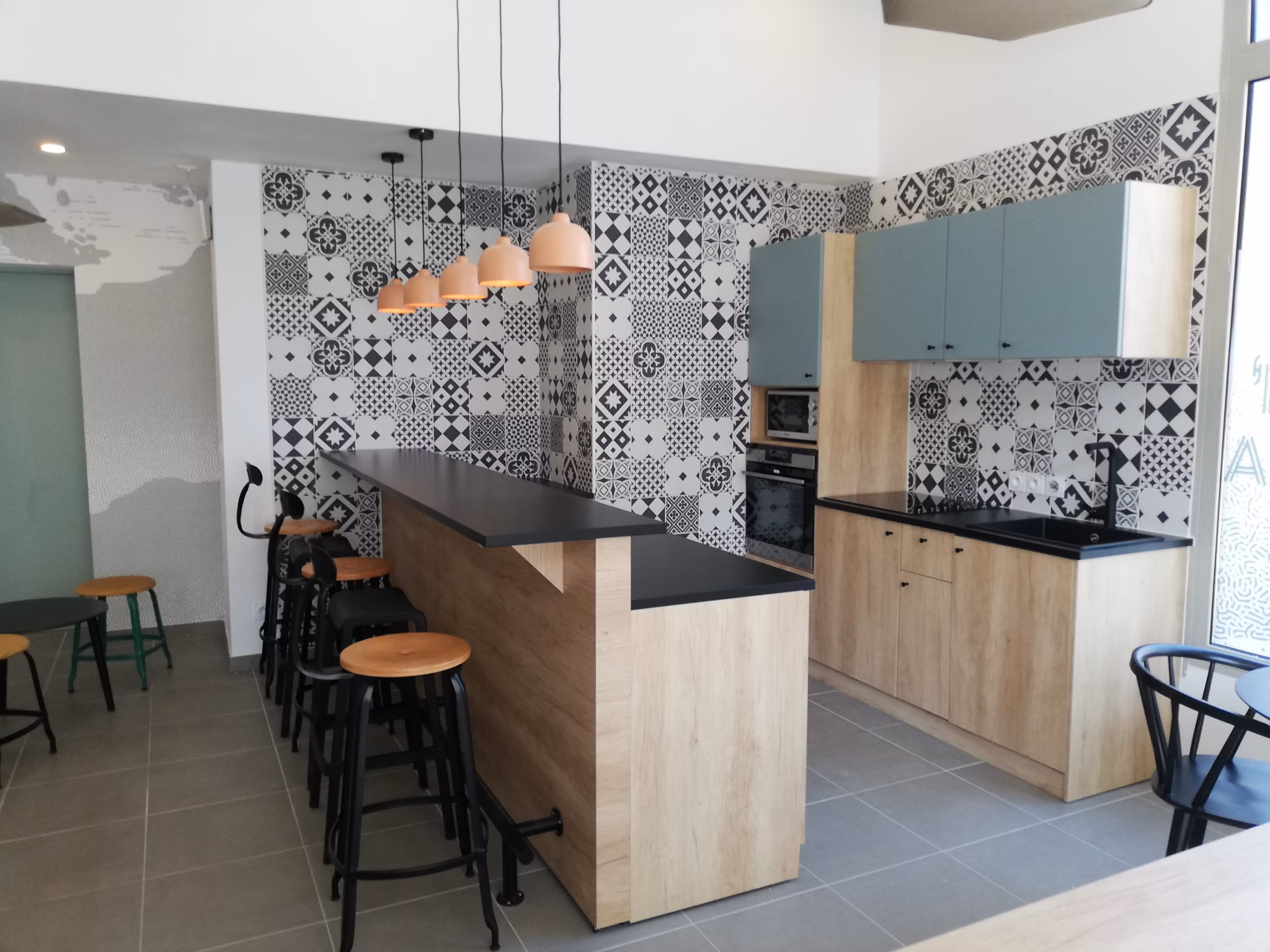 Modern kitchen with light wood cabinetry, black countertops, and decorative backsplash in a stylish open-plan layout.