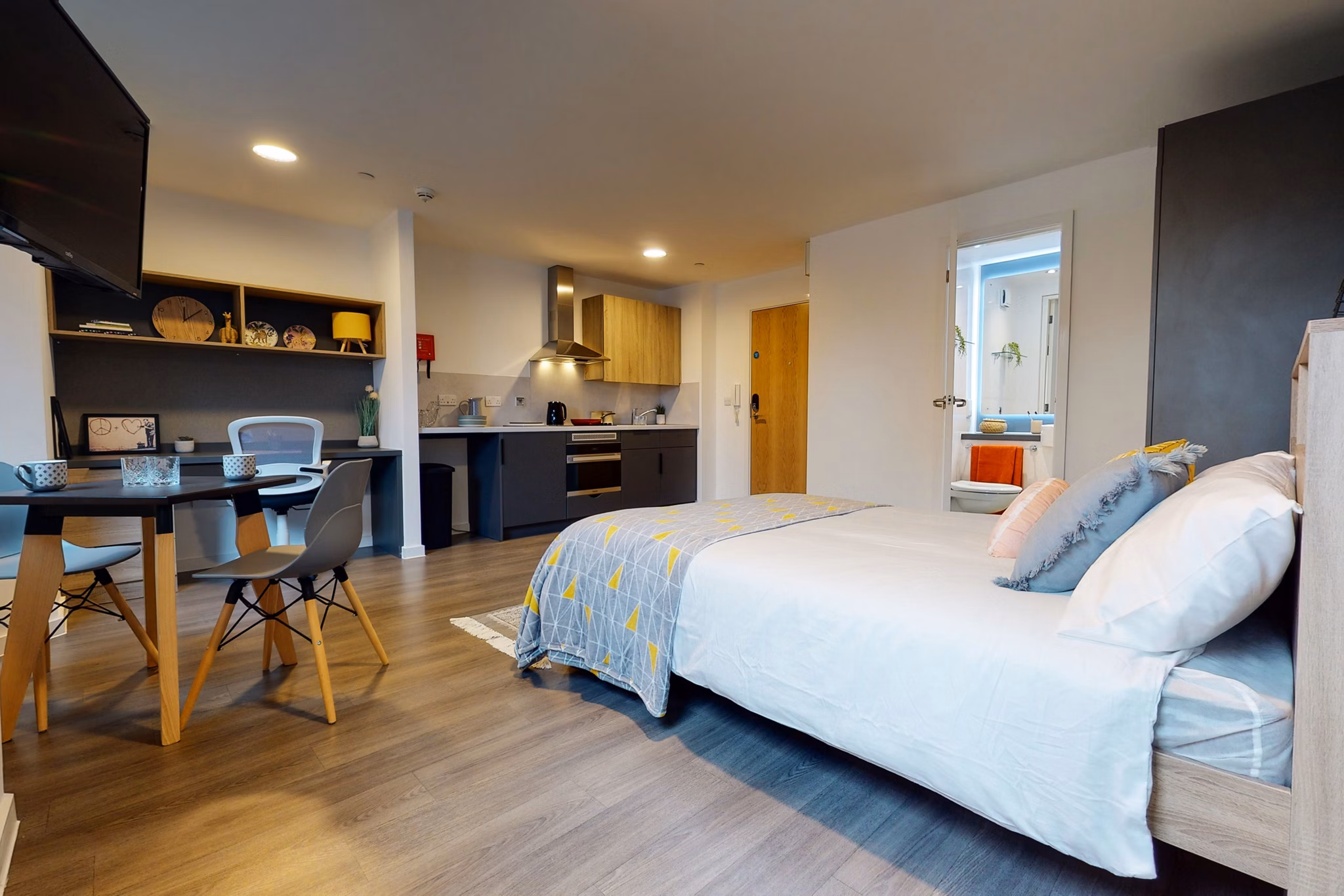 Bright and spacious living room area at Canvas Wembley apartments, featuring modern furniture, large windows, and wooden flooring.