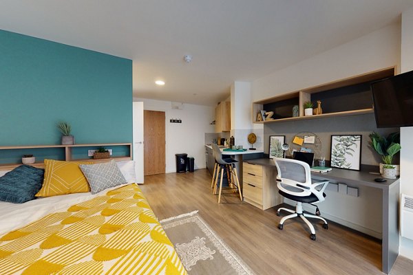 Modern student studio apartment at Canvas Coventry Arundel House in Coventry, featuring a cozy bed, study desk, open shelving, and kitchenette with natural light and stylish decor.