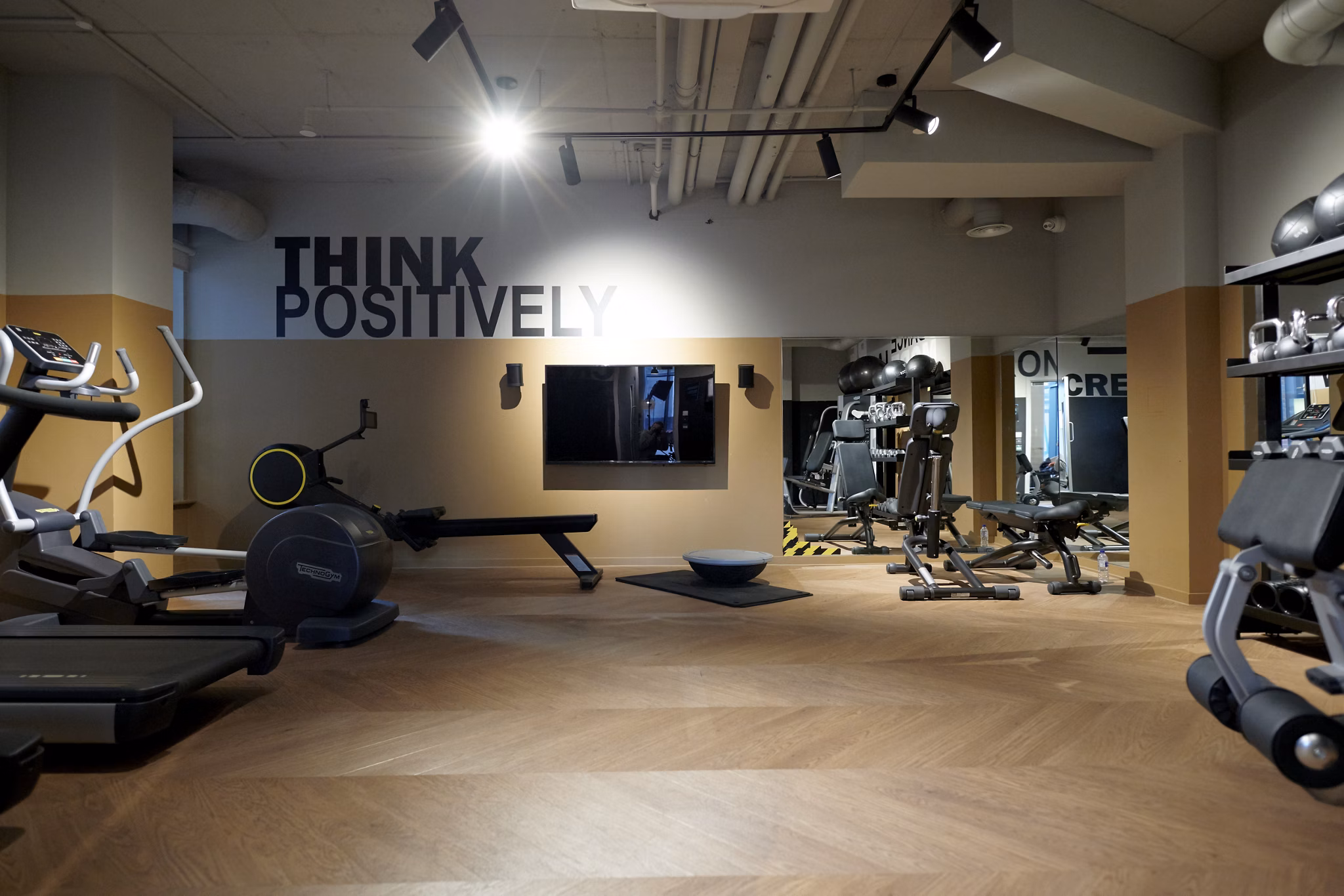 Modern gym facility at Canvas Coventry Arundel House in Coventry, featuring state-of-the-art equipment, motivational 'Think Positively' signage, and warm wooden flooring.