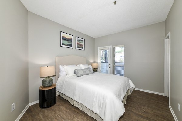 Cozy bedroom with large windows at Avana Dunwoody Apartments featuring modern design elements