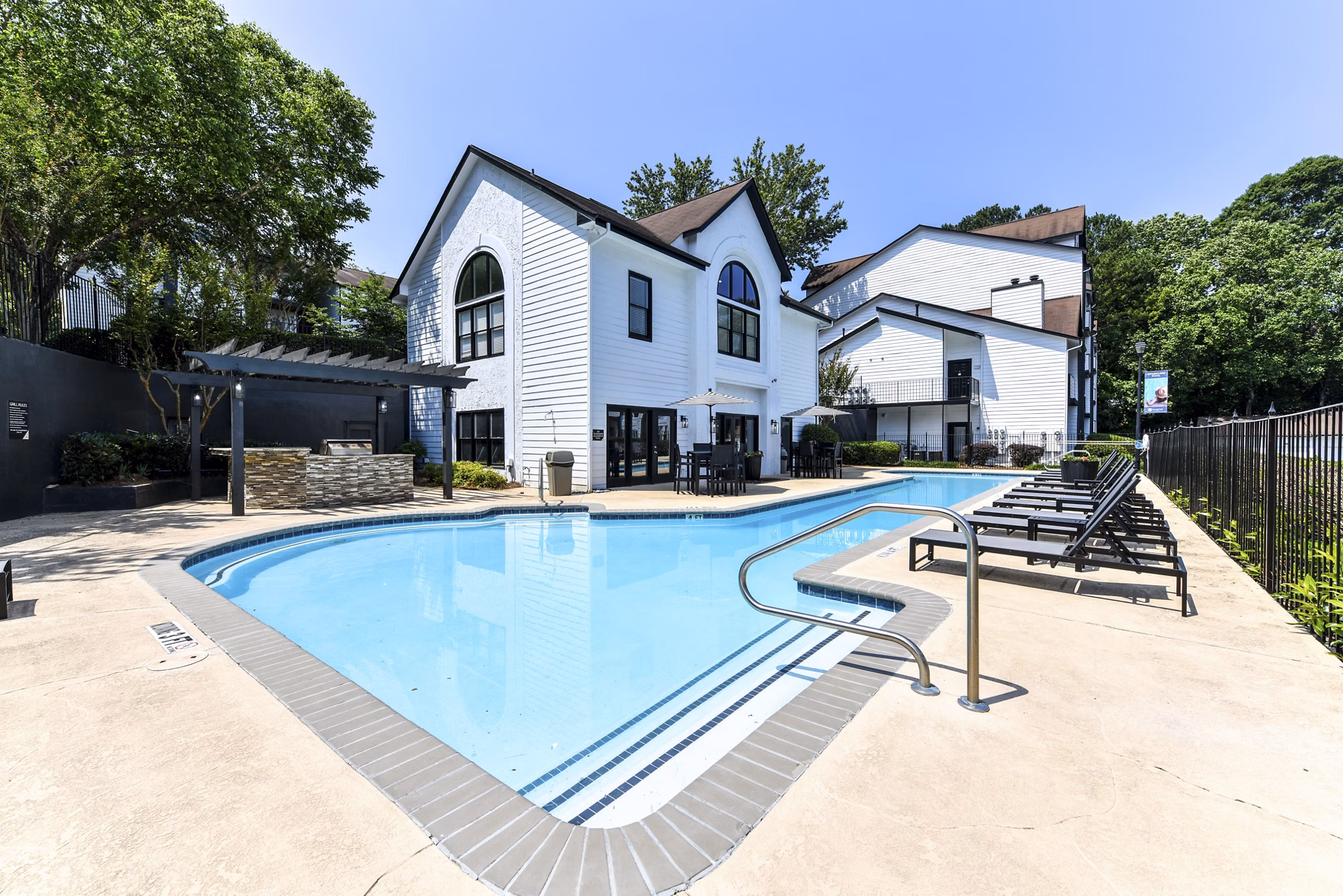 Luxurious pool at Avana Dunwoody Apartments featuring modern lounge chairs and lush landscaping