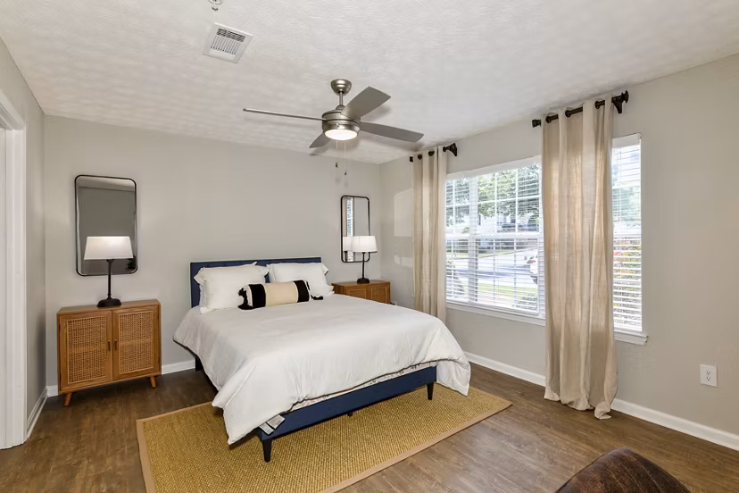 Cozy bedroom featuring modern decor and large windows at Avana Twenty9 Apartments