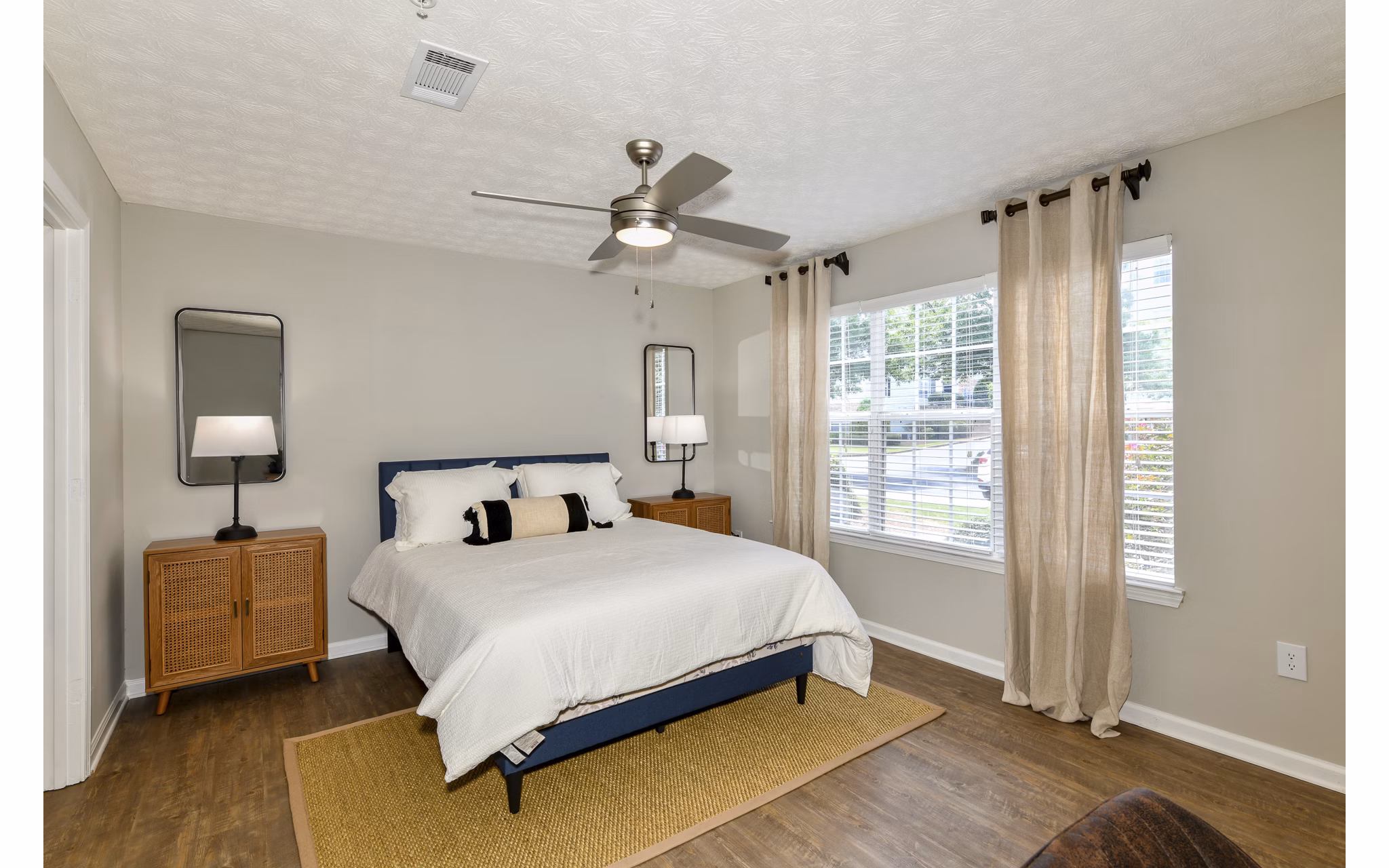 Cozy bedroom featuring modern decor and large windows at Avana Twenty9 Apartments