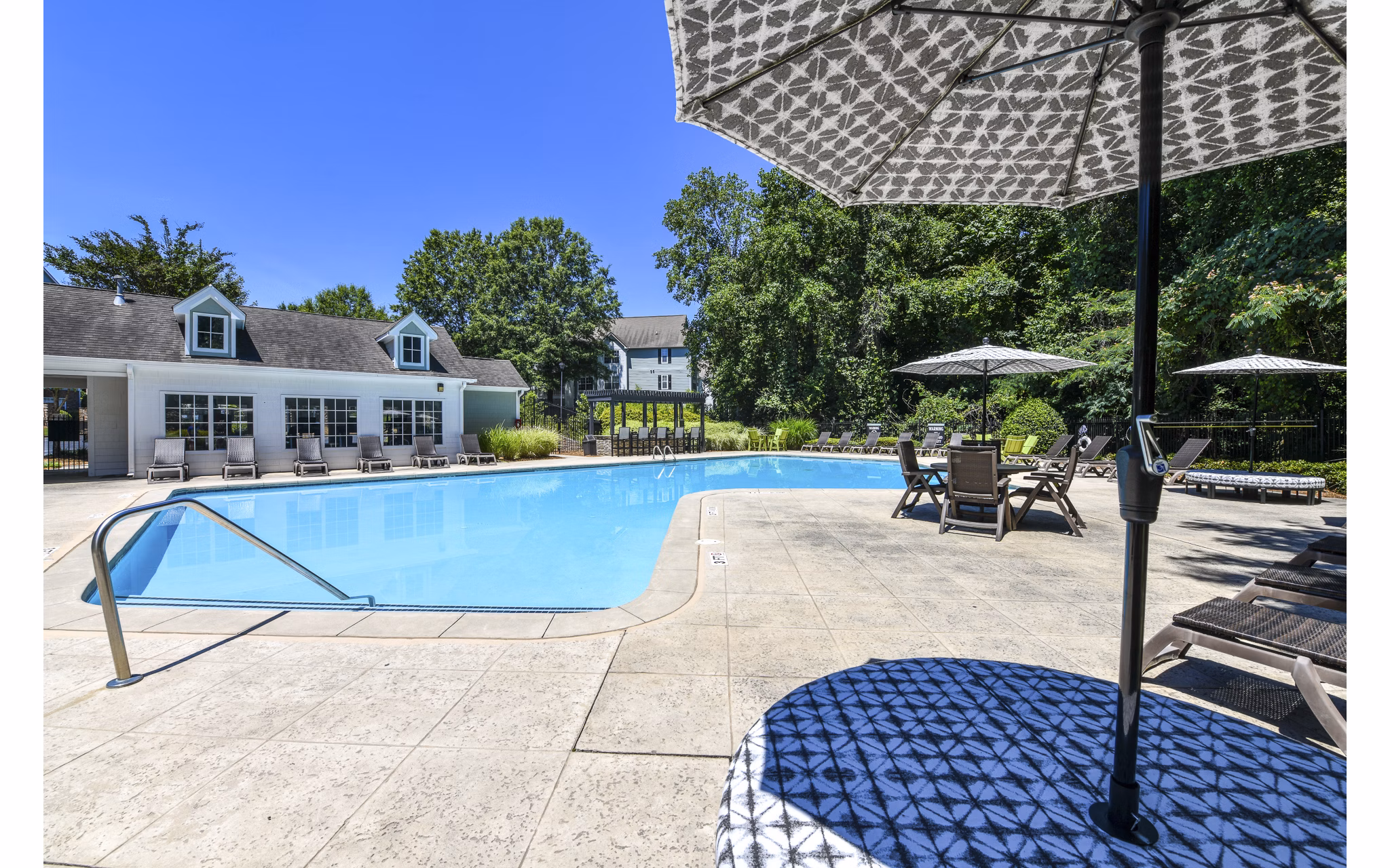 Outdoor pool with lounge chairs and landscaped surroundings at Avana Twenty9 Apartments