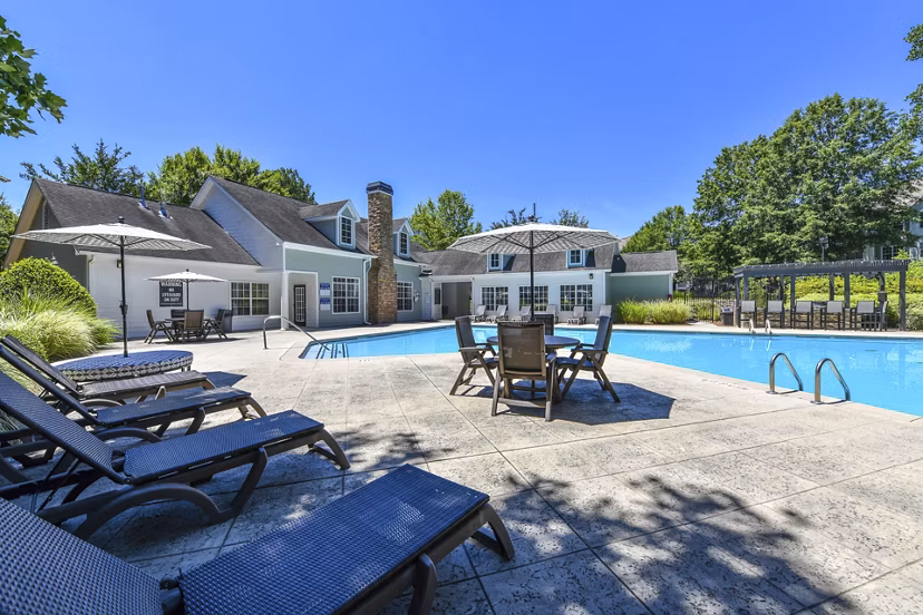 Sparkling outdoor pool at Avana Twenty9 Apartments with lounge chairs and umbrellas