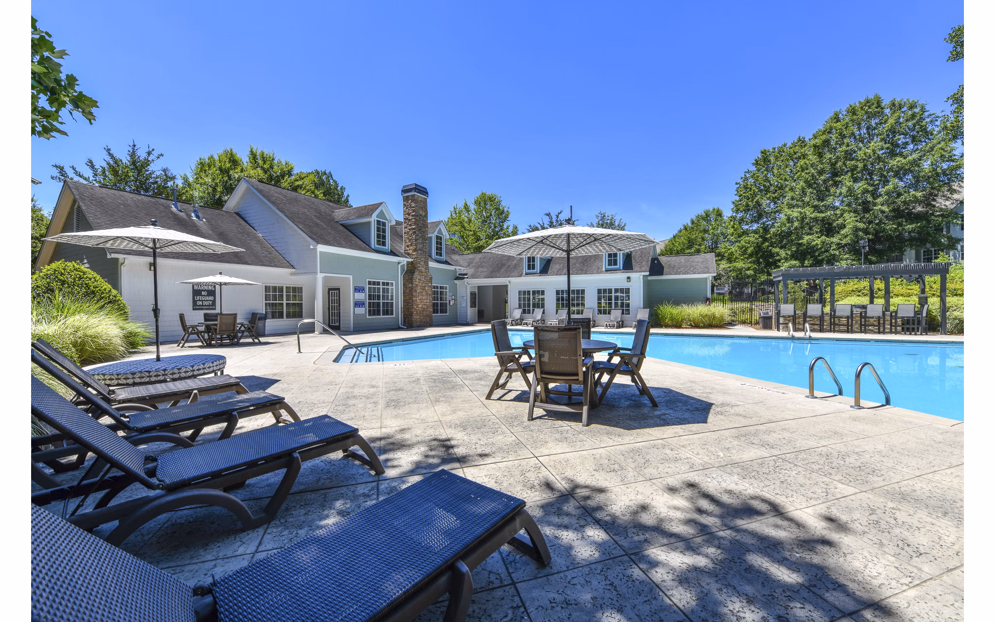 Sparkling outdoor pool at Avana Twenty9 Apartments with lounge chairs and umbrellas