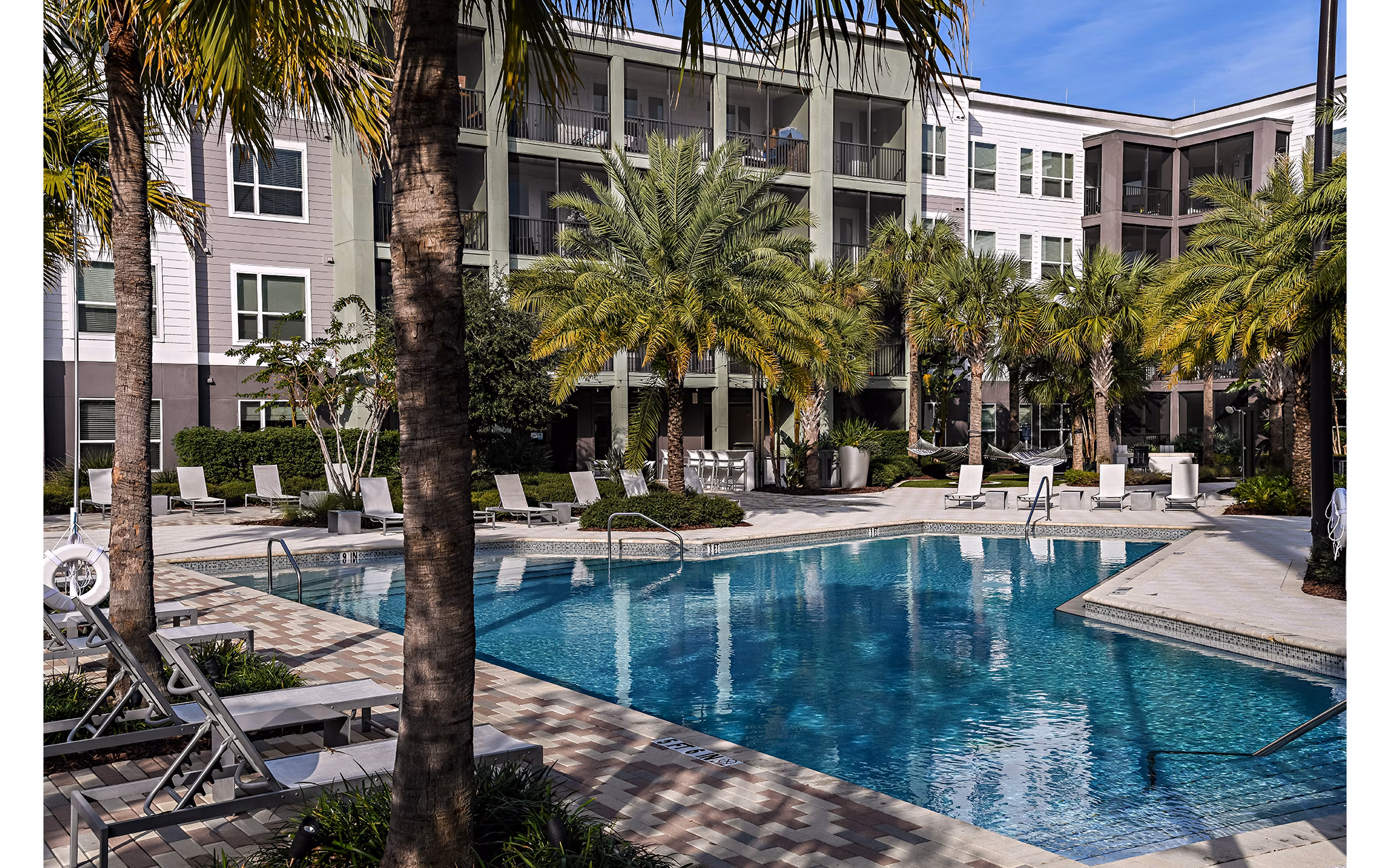 Luxurious pool area at Kestra Apartments with comfortable lounge seating and lush landscaping