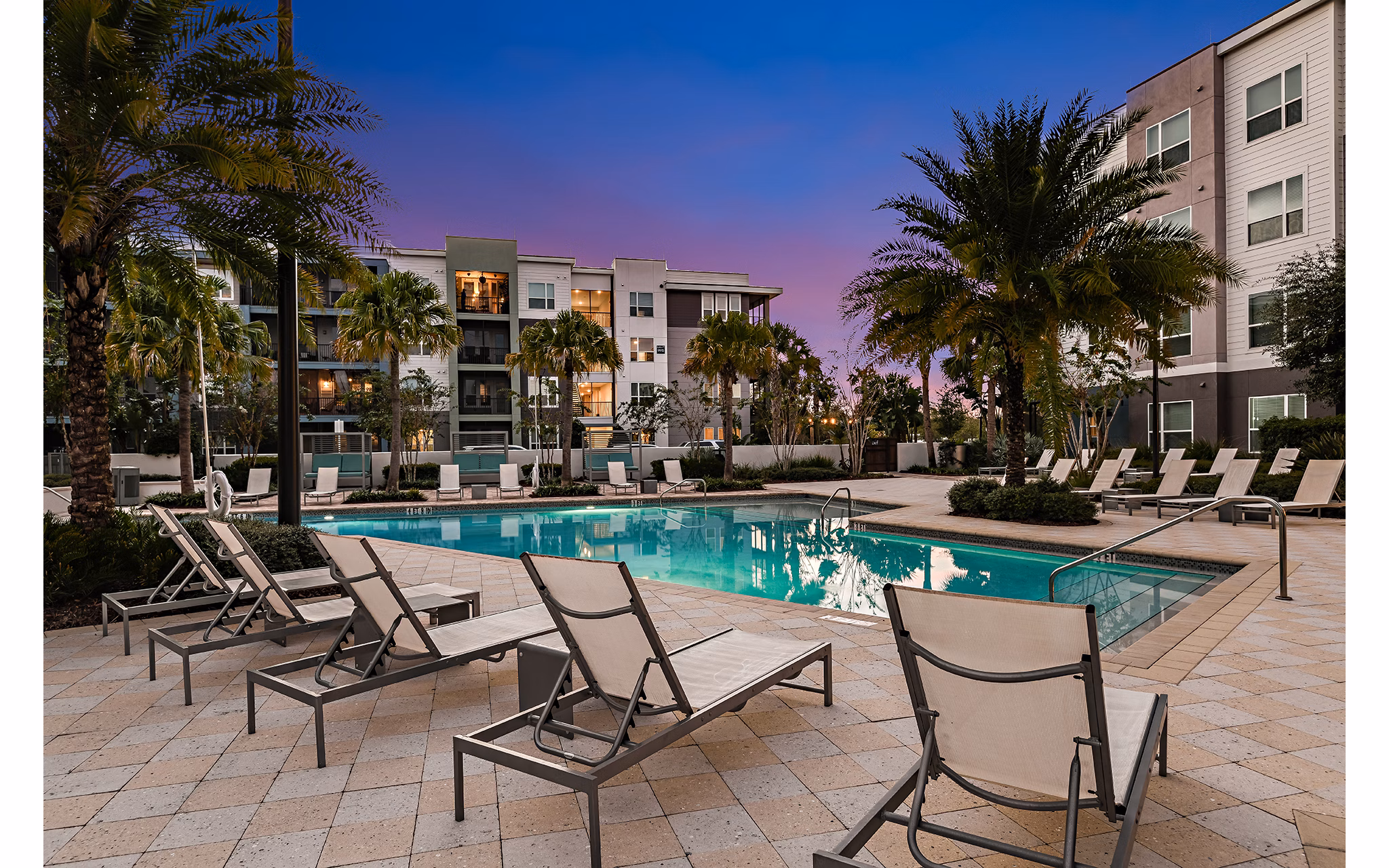 Luxury pool area at Kestra Apartments, featuring modern lounge chairs and lush landscaping, perfect for relaxation and recreation