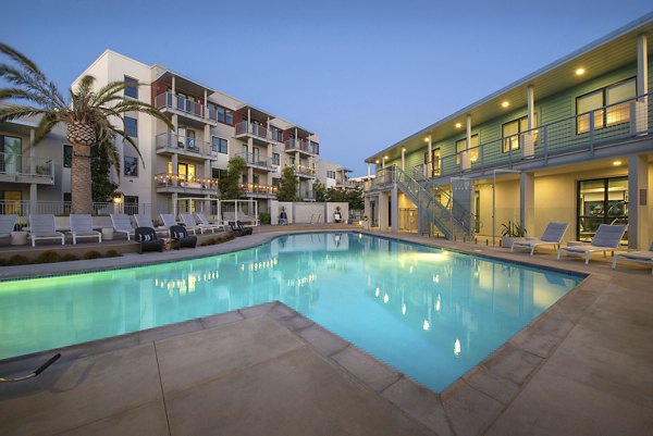 Resort-style swimming pool at Coastline Ventura Apartments featuring lush landscaping and sun loungers