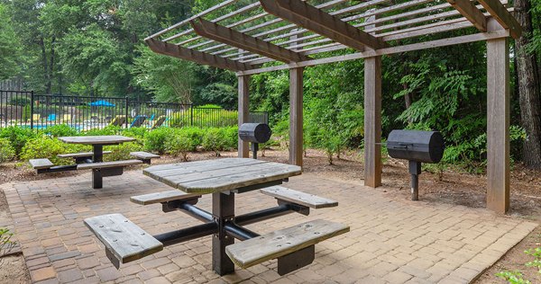 Outdoor grill area with seating and greenery at Somerset at the Crossings Apartments, ideal for social gatherings and barbecues