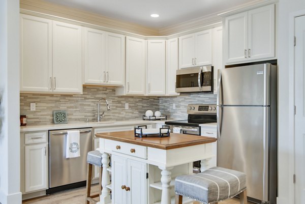 Modern kitchen with quartz countertops and stainless steel appliances at Vistas of Port Jefferson Apartments