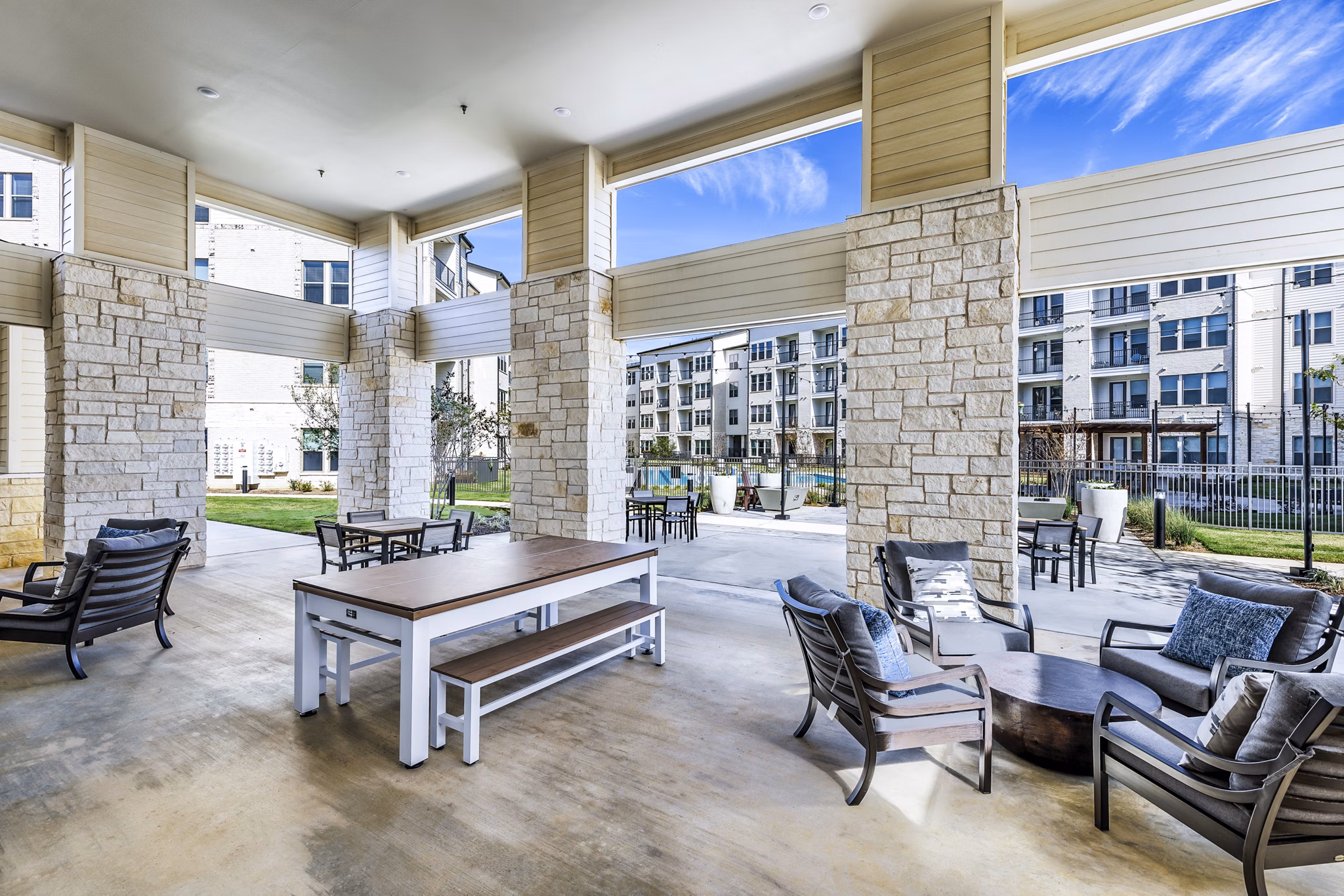 Modern outdoor patio at Album Mansfield Apartments with seating and lush greenery, ideal for relaxation and gatherings
