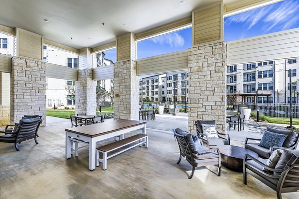 Modern outdoor patio at Album Mansfield Apartments with seating and lush greenery, ideal for relaxation and gatherings